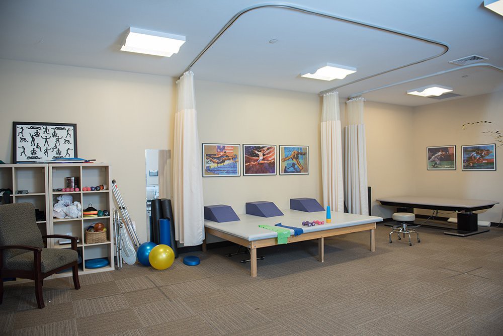 A physical therapy room equipped with exercise balls, foam rollers, and therapy tables.
