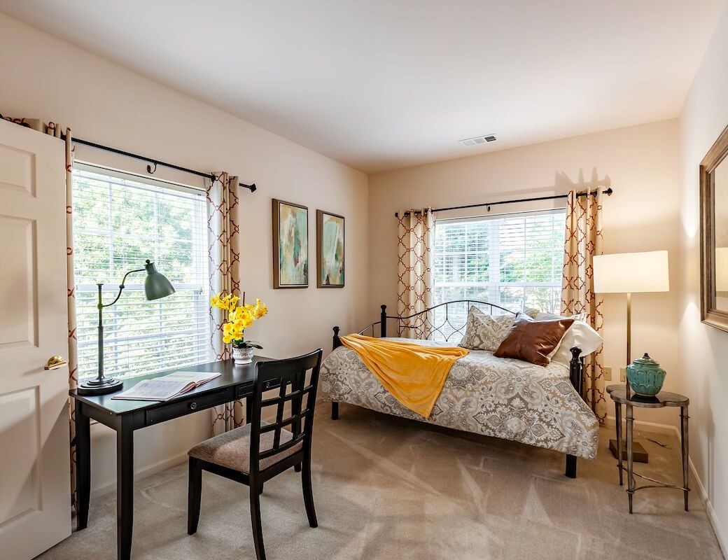 A cozy bedroom with a desk and natural lighting.
