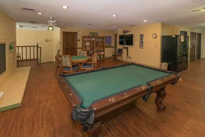 A cozy recreation room featuring a pool table, seating area, and television.