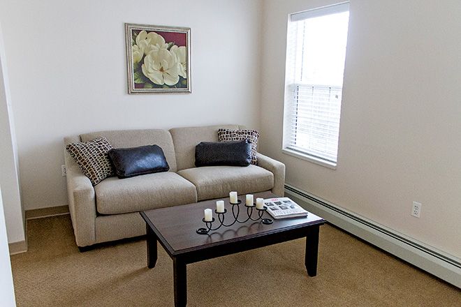 A cozy living room with a sofa and coffee table, decorated with a candle holder and wall art.