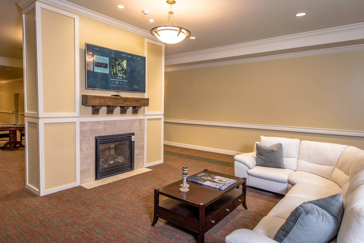 A modern living room with a fireplace and mounted television, featuring comfortable seating and stylish decor.