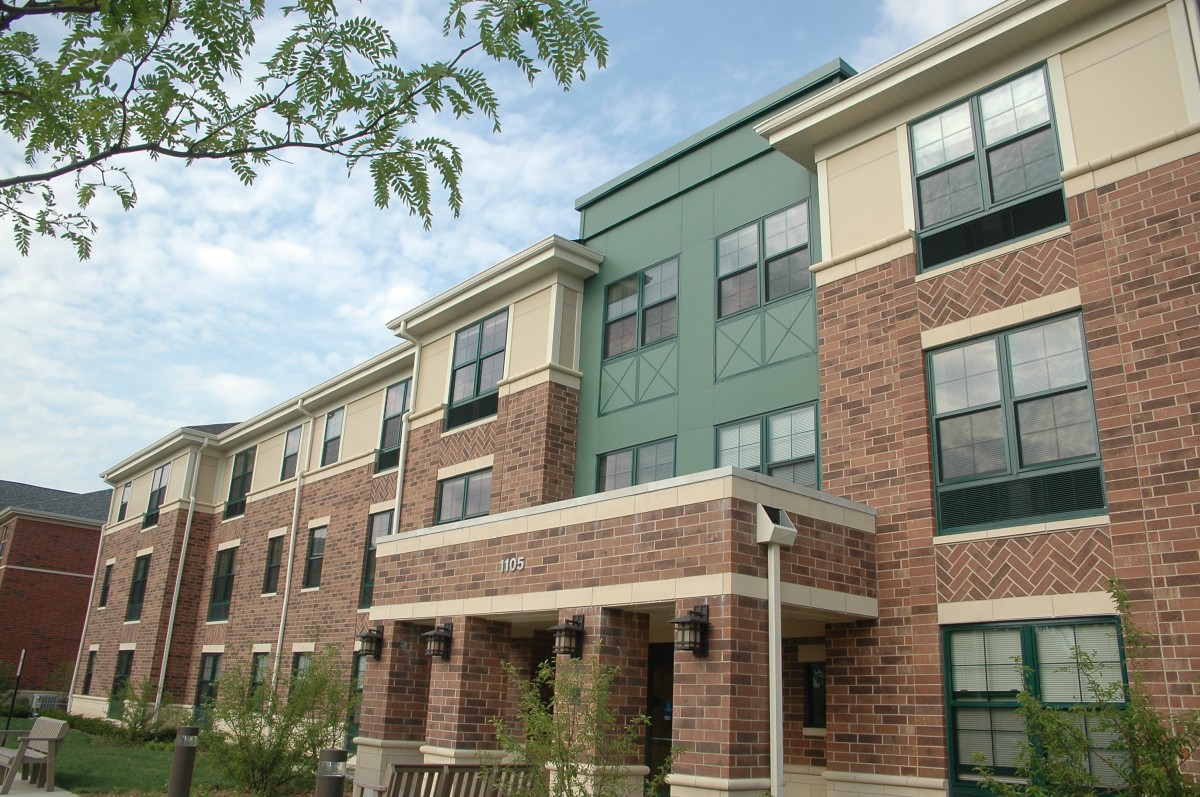 A modern apartment building with a brick facade and multiple windows.