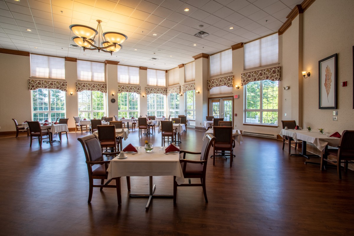 A spacious and elegant dining room with neatly arranged tables and large windows.