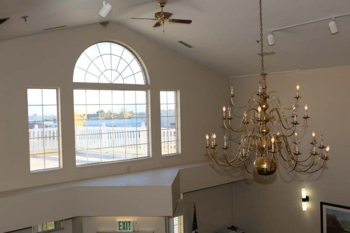 A bright interior space featuring a large chandelier and expansive arched windows.