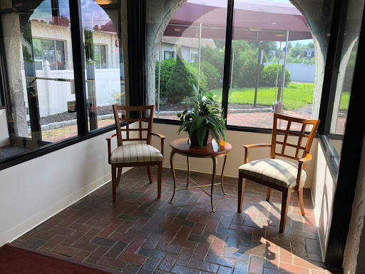 A bright and inviting seating area with two chairs and a small table, surrounded by large windows that let in natural light.