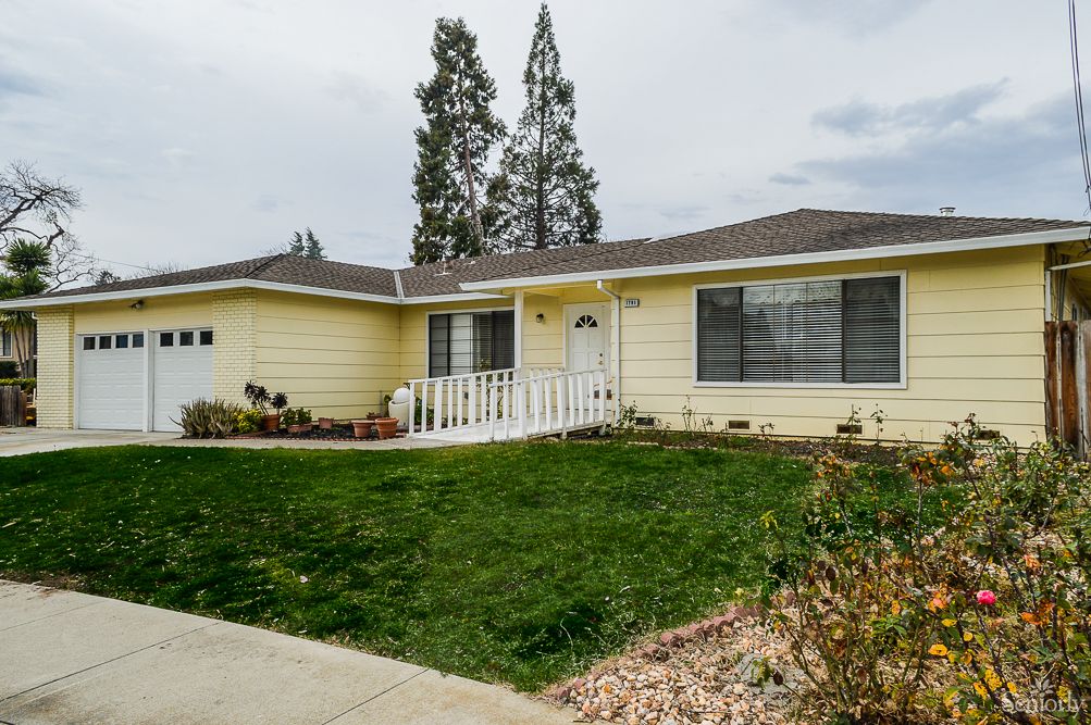 A suburban yellow house with a well-kept front yard and driveway.