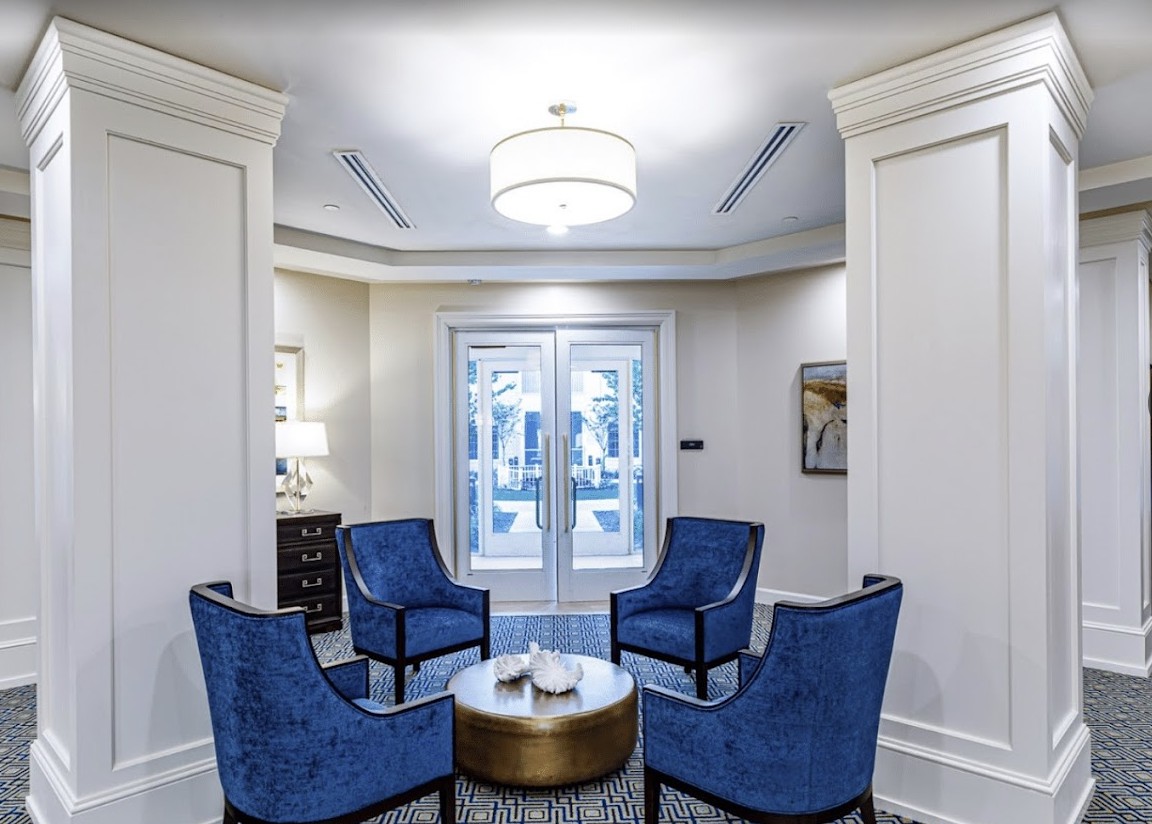A stylish seating area with four blue chairs surrounding a round table, featuring modern lighting and elegant decor.