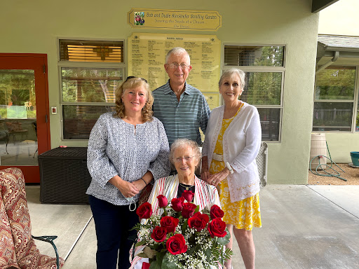 A lovely family gathering celebrating a special occasion with a beautiful bouquet of red roses.