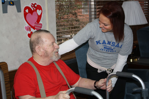 A caregiver engages with an elderly man, sharing a warm moment of support and interaction.