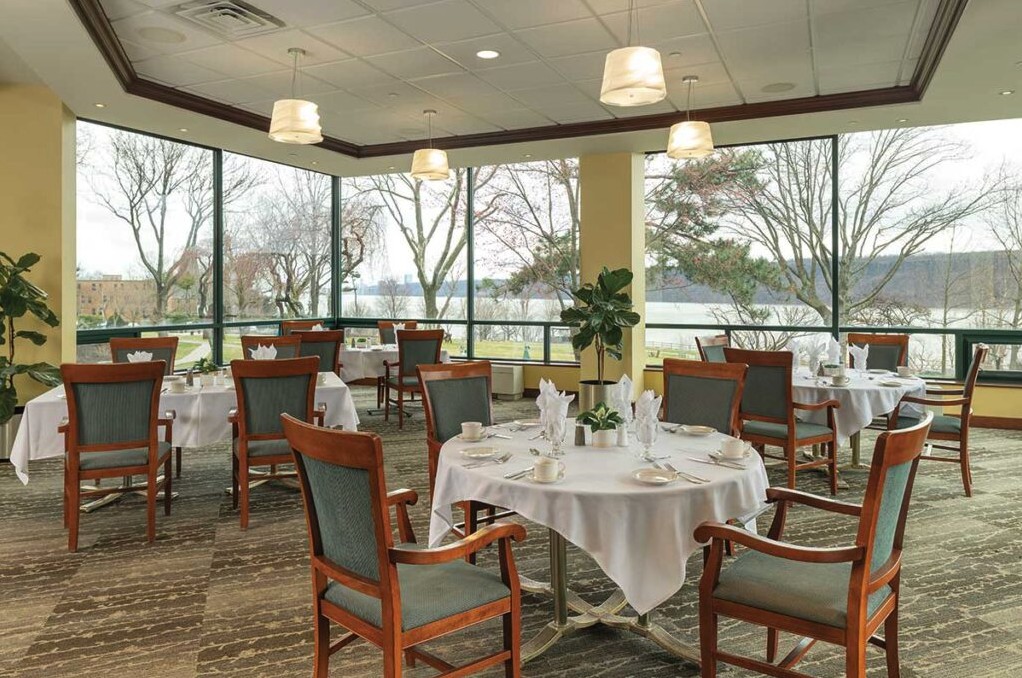 A spacious dining area with neatly set tables and large windows overlooking a scenic view.