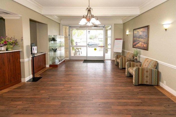 A spacious lobby area with wooden flooring, comfortable seating, and a bright entrance.