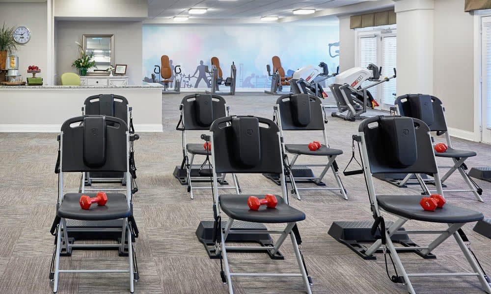 A fitness room equipped with chairs and dumbbells, ready for a group exercise session.