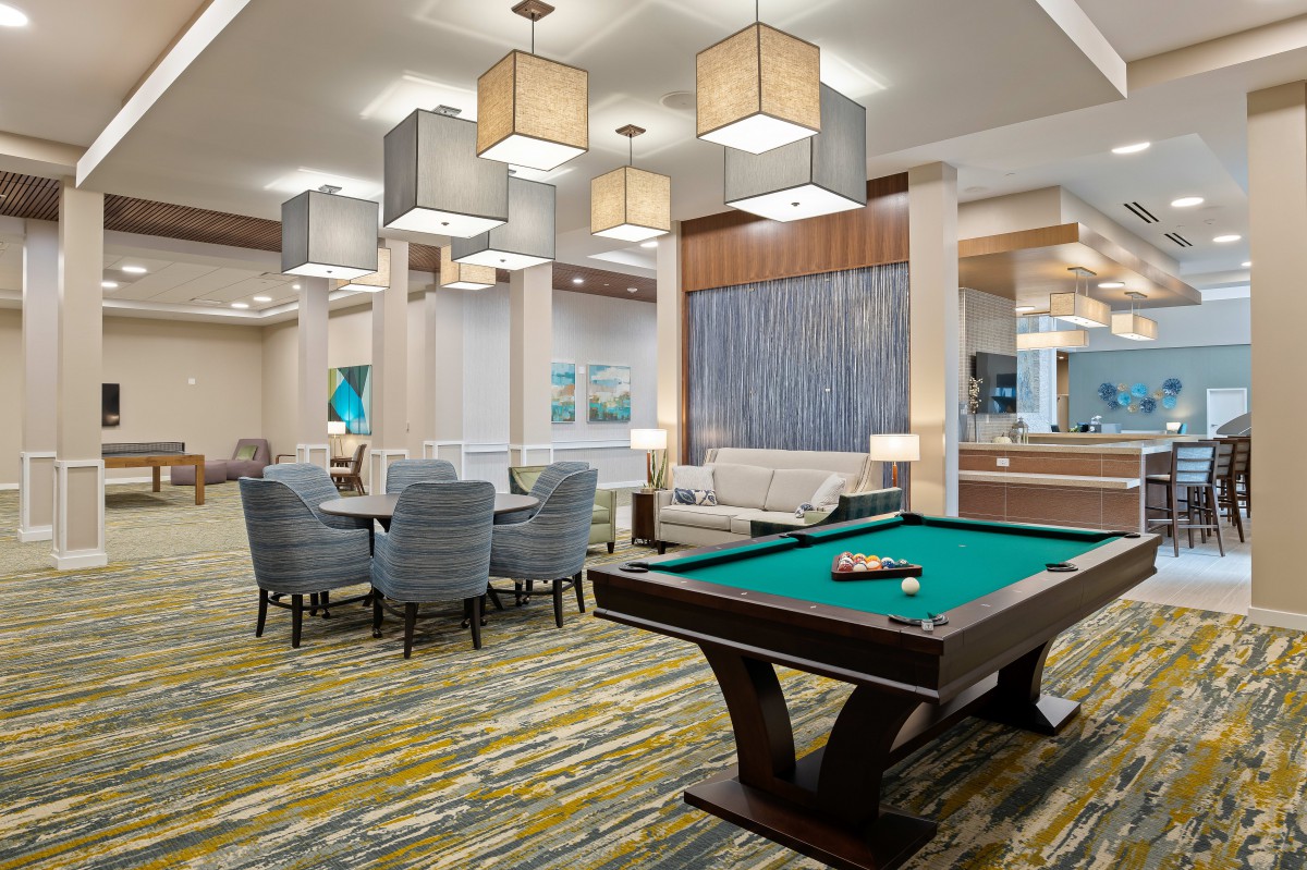 A modern lounge area featuring a billiards table and comfortable seating.