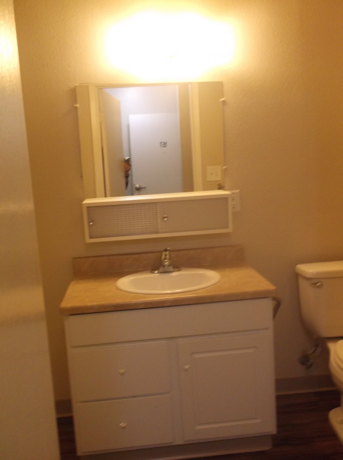 A clean and simple bathroom with a sink, mirror, and toilet.