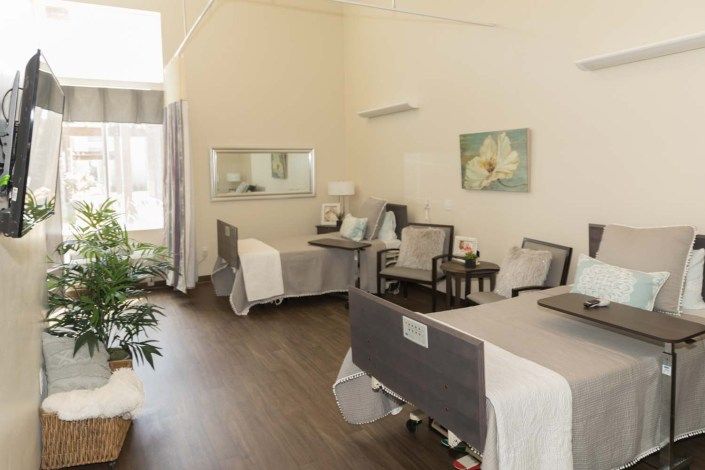 A well-lit hospital room with two beds and comfortable seating.