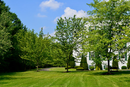 A serene house surrounded by lush greenery and a well-maintained lawn under a clear blue sky.