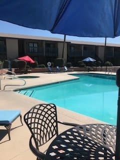 A sunny day at an outdoor swimming pool with lounge chairs and colorful umbrellas.