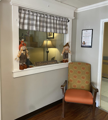 A cozy room featuring a window adorned with decorative dolls and an inviting chair.