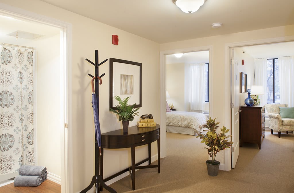 A modern hallway with decorative plants and furniture leading to a bedroom.