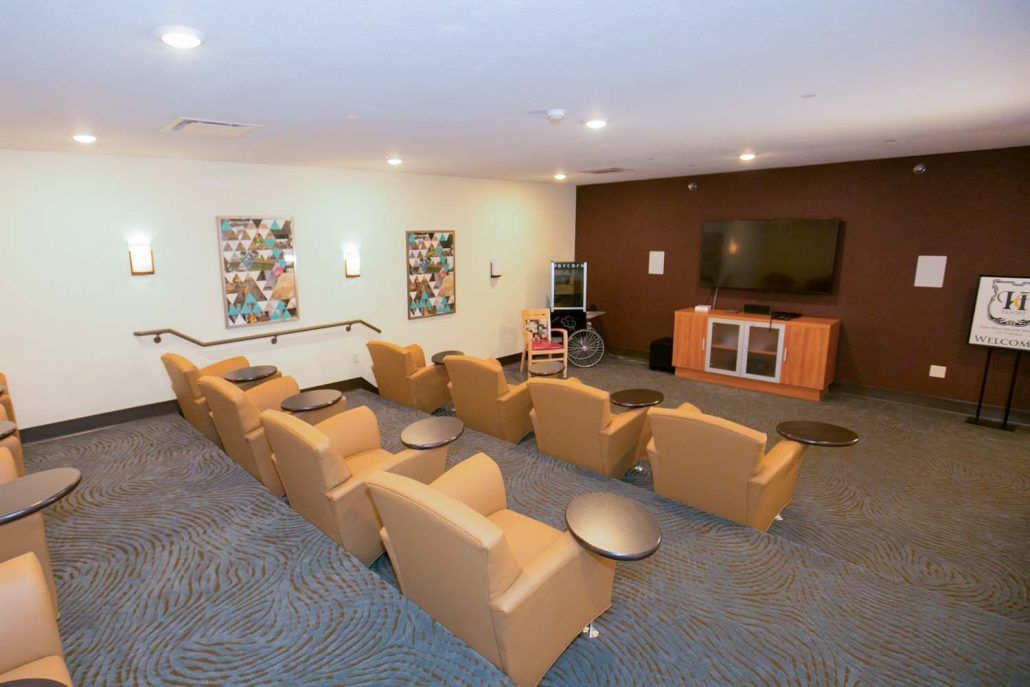 A small home theater room with several comfortable chairs facing a large television screen.