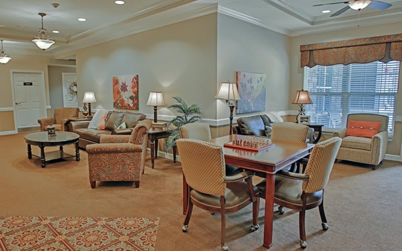 A cozy and elegantly designed living room featuring comfortable seating, a table with chairs, warm lighting, and decorative artwork on the walls.