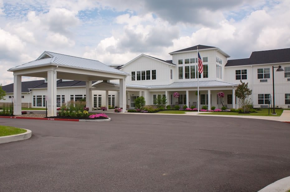 A large building with a covered entrance and an expansive driveway under a cloudy sky.