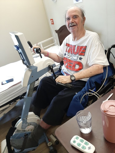 An elderly person engaged in a cycling exercise while seated in a wheelchair.