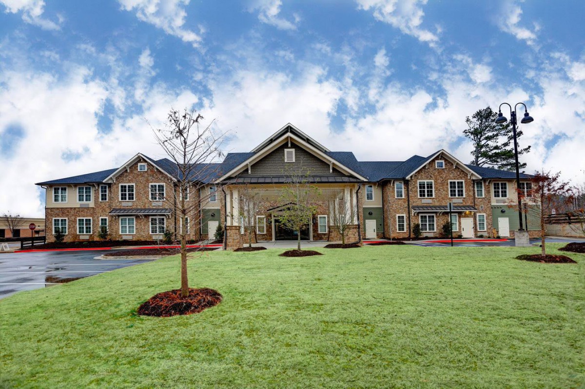 A large residential building with a well-maintained lawn and clear sky.