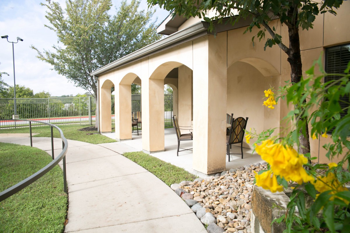 A charming patio with arches and seating, surrounded by a garden path.