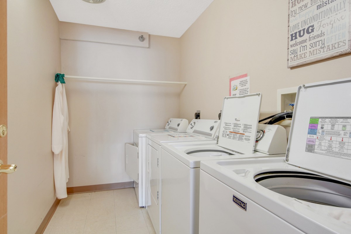 A clean and organized laundry room with multiple washing machines and dryers.
