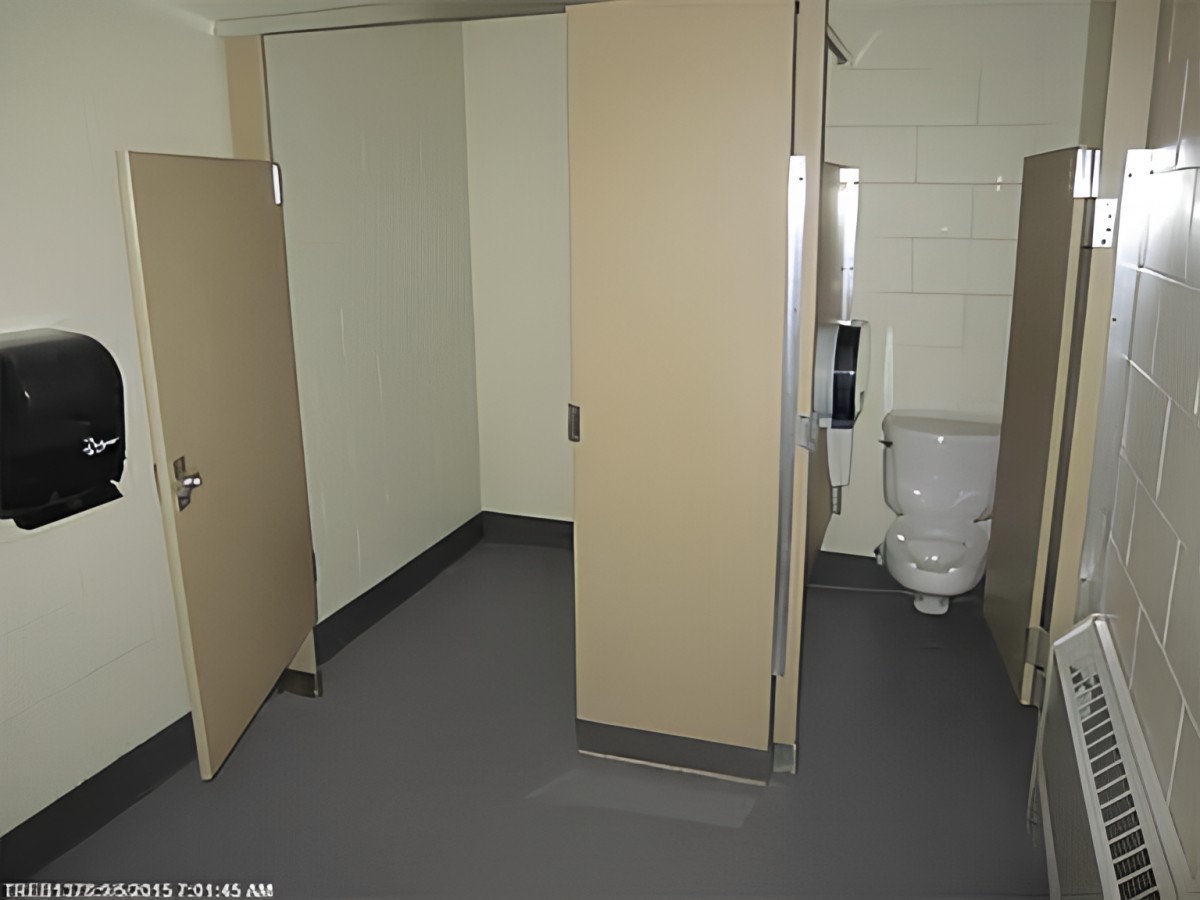 A public restroom featuring a toilet stall and open door.