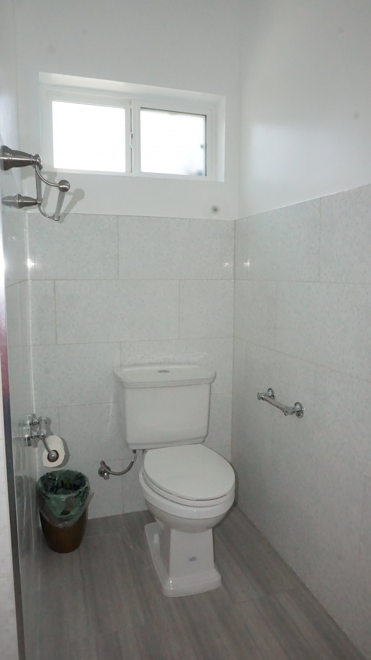 A small bathroom with a toilet and white tiled walls.