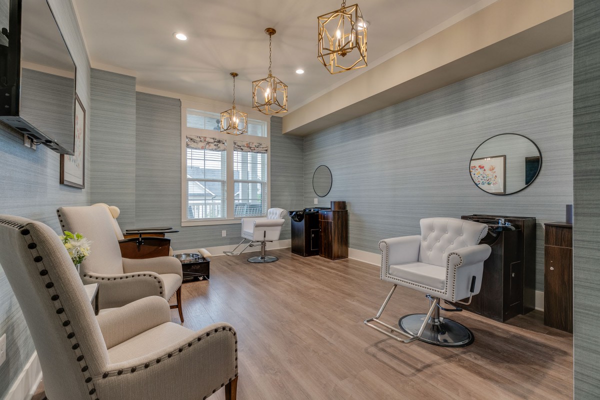 A stylish and elegant salon interior with comfortable chairs, modern lighting, and a large window.