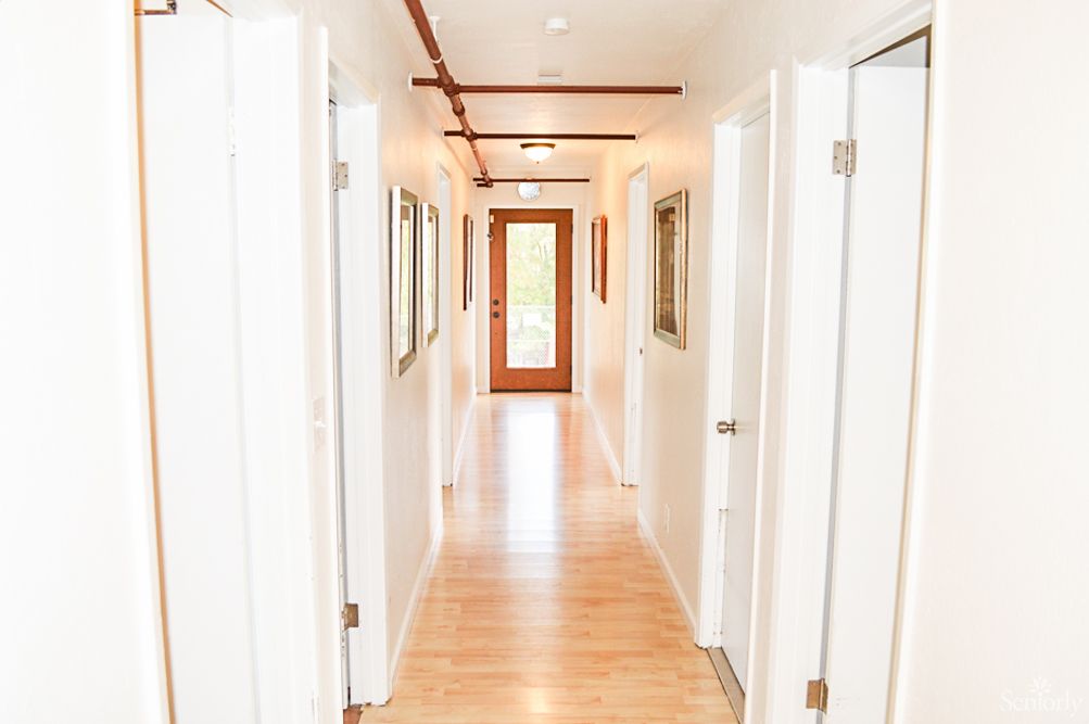 A brightly lit modern hallway with wooden flooring and multiple doors.