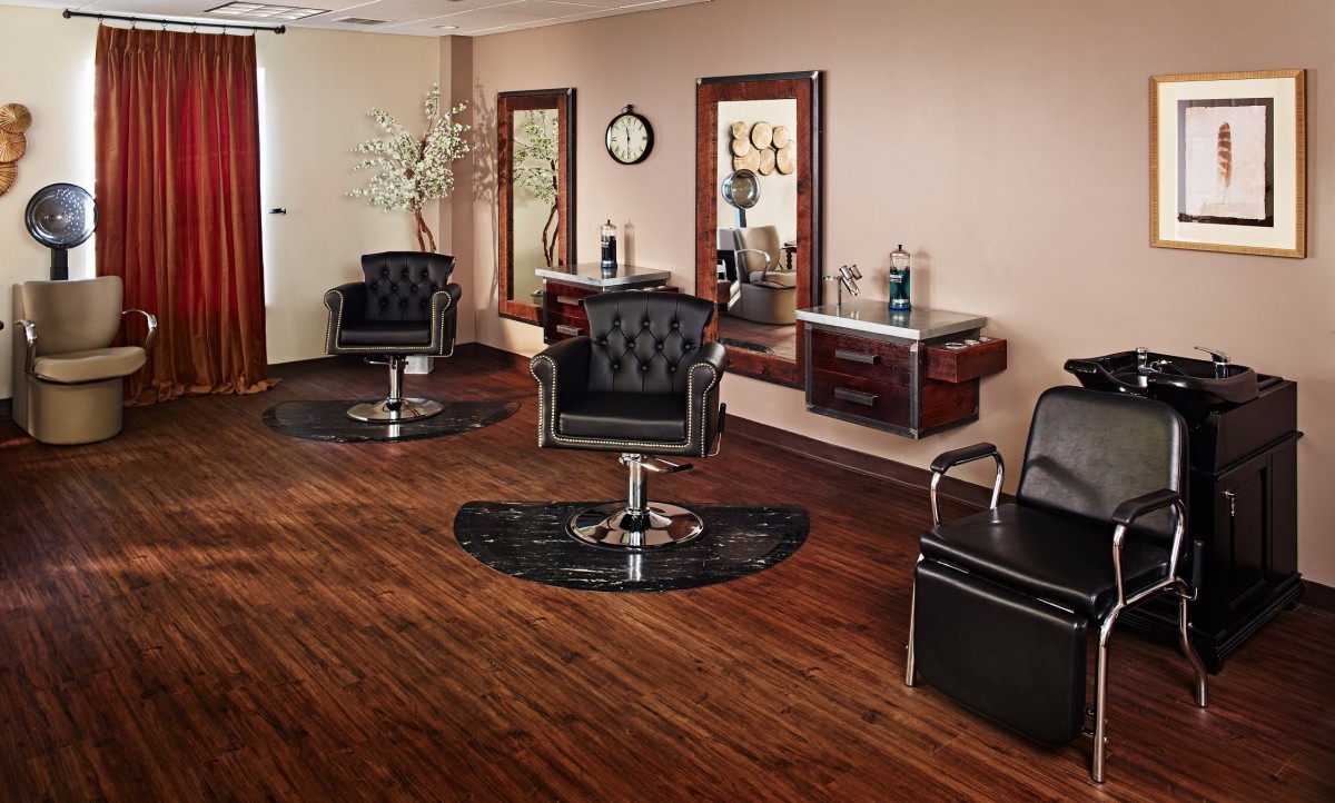A stylish and modern hair salon interior with black leather chairs and large mirrors.