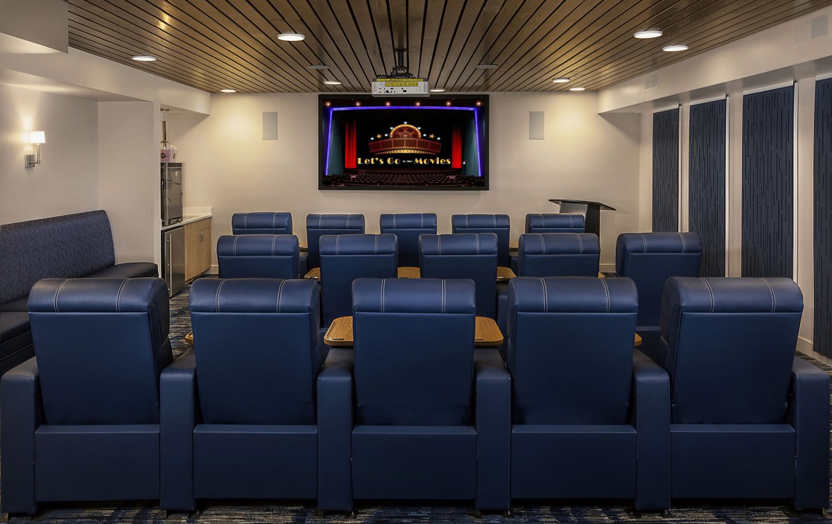 A luxurious home theater setup with comfortable blue seating and a large screen, designed for an immersive entertainment experience.