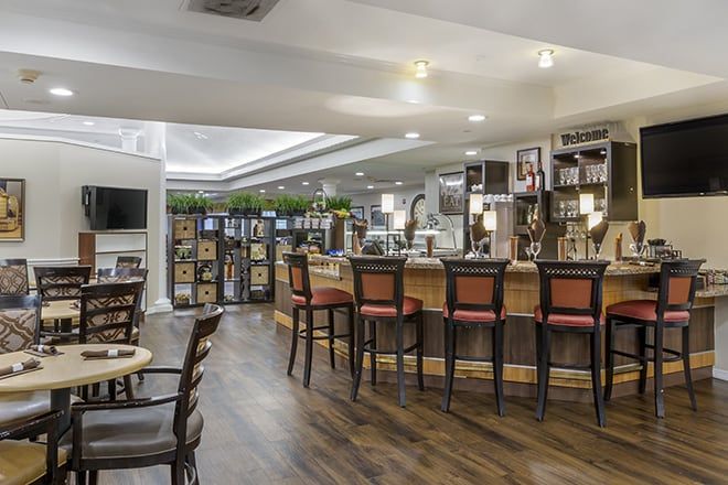 A modern bar and restaurant interior with sleek wooden flooring, a well-lit counter, and comfortable seating.