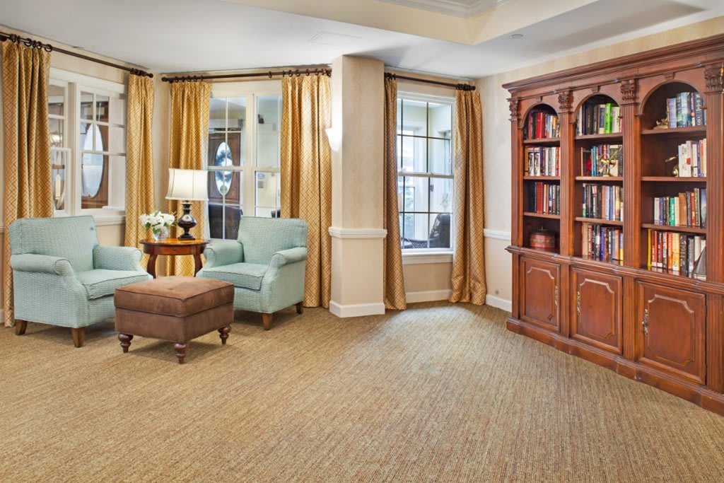 A cozy living room with a comfortable armchair, a wooden bookshelf, and warm curtains.