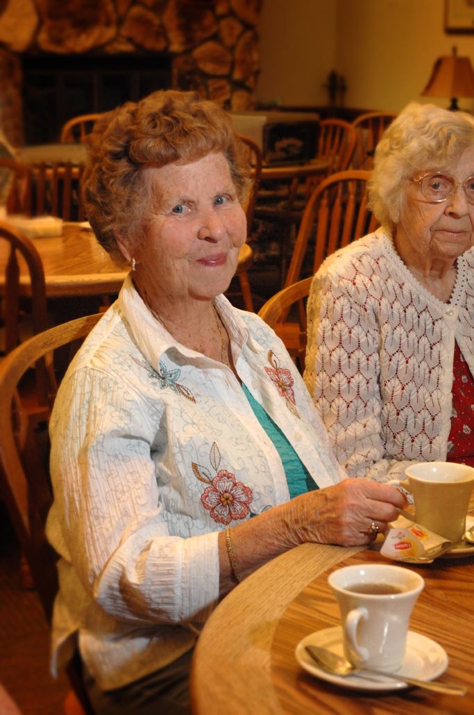 Two elderly women enjoying tea in a cafe.