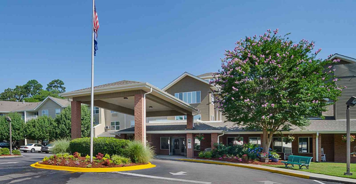 A welcoming building entrance with a flagpole and landscaped surroundings.