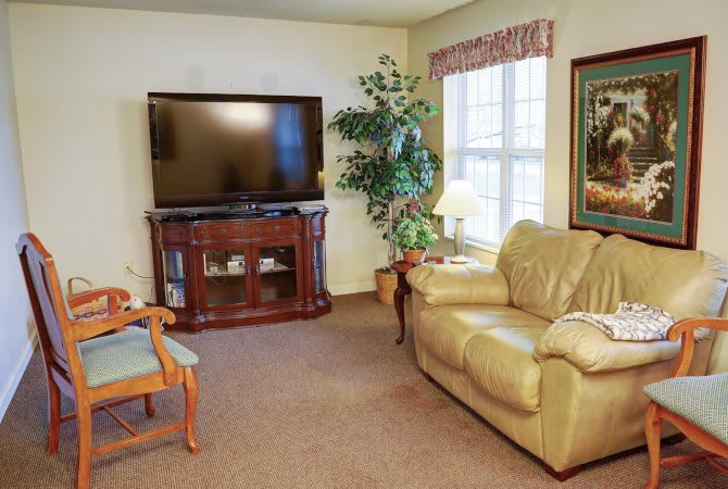 A cozy living room with a sofa, TV, and natural light from large windows.