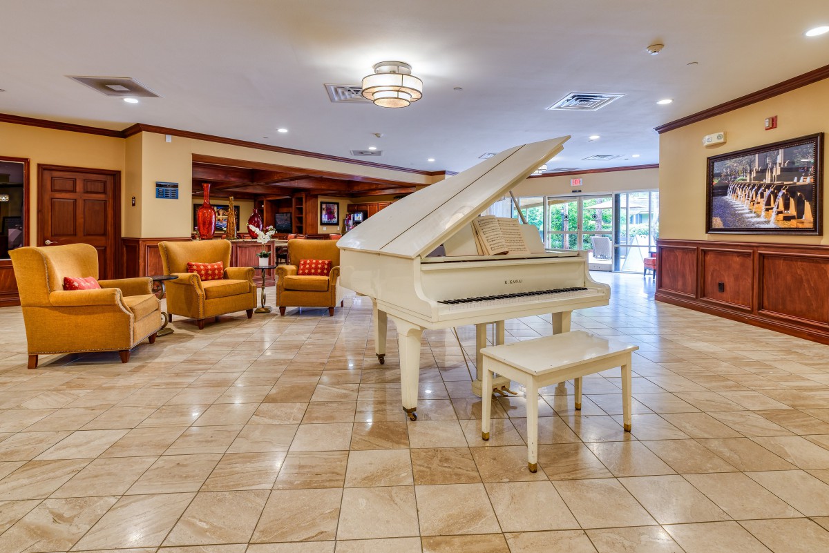 A modern hotel lobby featuring a white grand piano and a comfortable seating area.