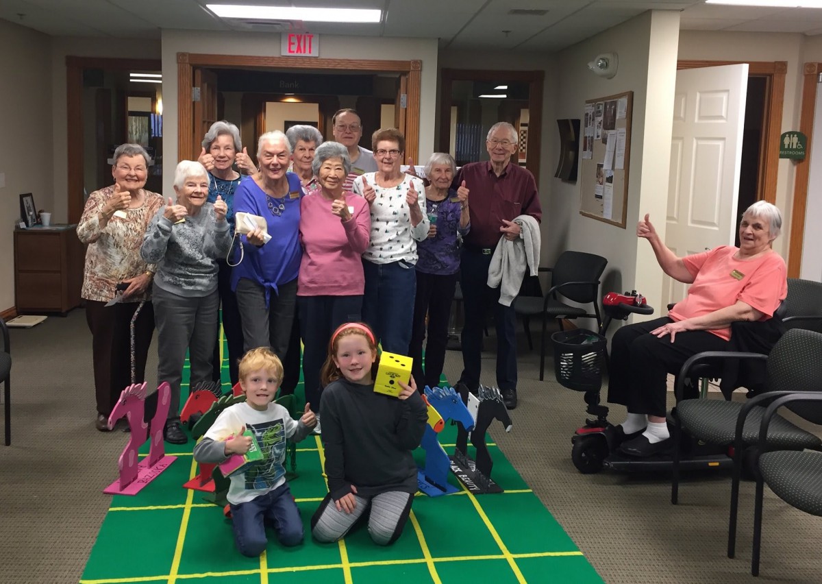 A group of seniors and children enjoying a game together indoors.