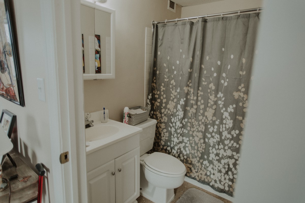 A small bathroom featuring a sink, toilet, and a floral patterned shower curtain.