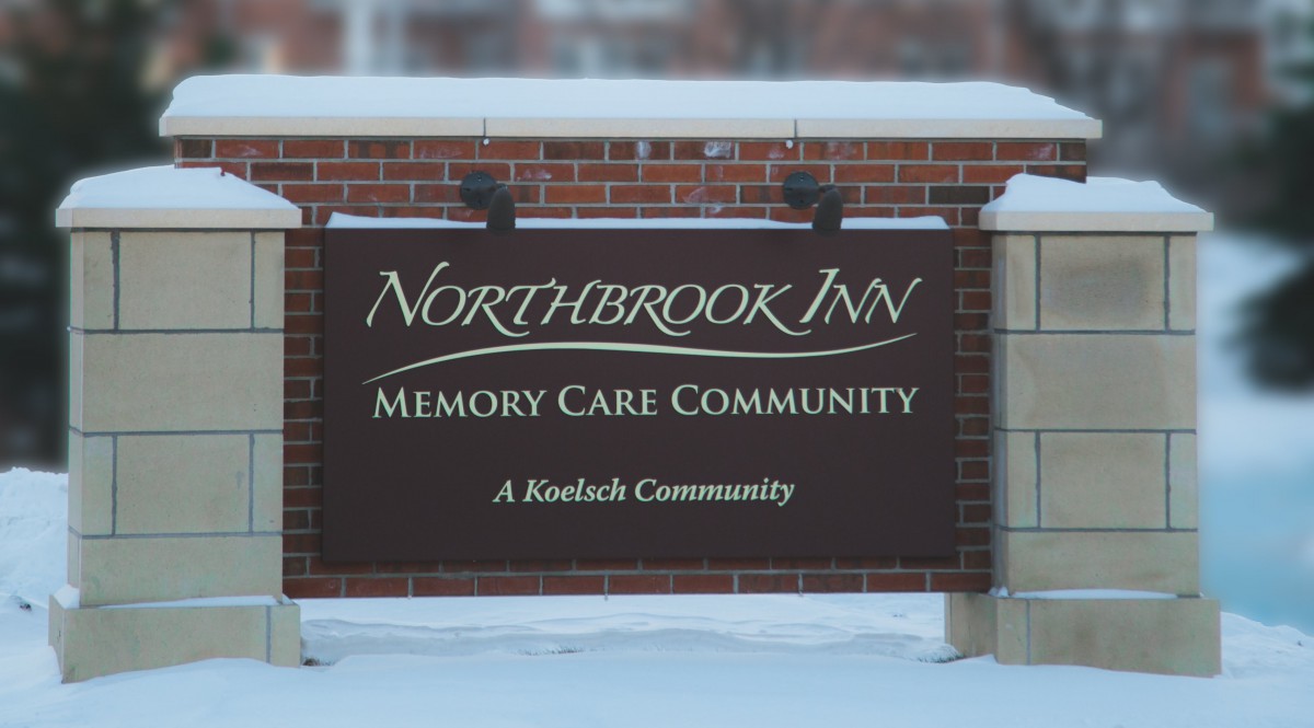 Sign for Northbrook Inn Memory Care Community, located in a snowy setting.