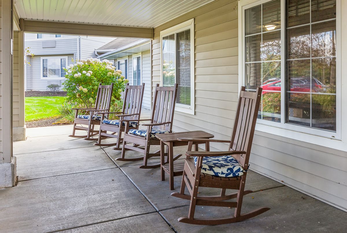 A cozy porch with wooden rocking chairs and floral cushions, providing a welcoming outdoor seating area.