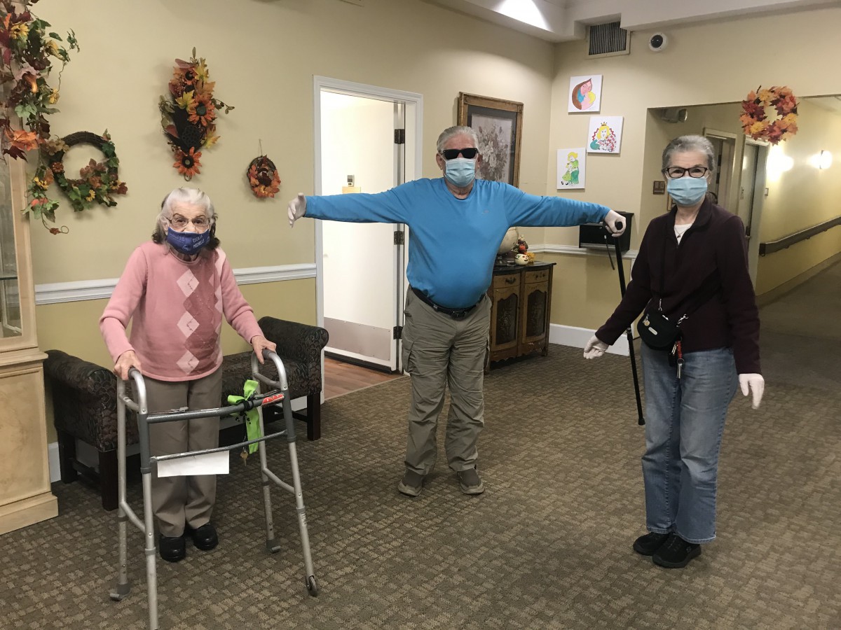 Three seniors practice social distancing and wear masks indoors.