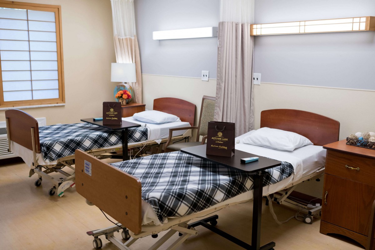 A well-organized hospital room with two neatly made beds, equipped with bedside tables and surrounded by a clean, welcoming environment.