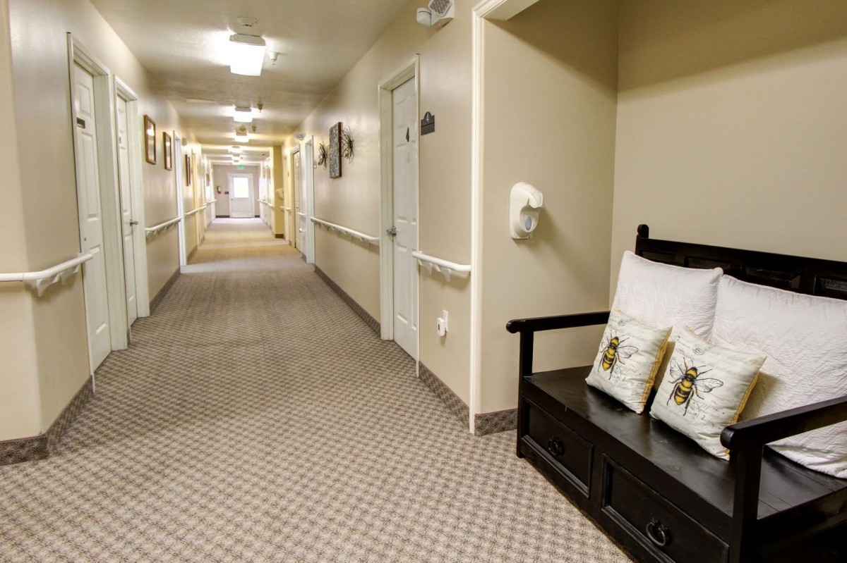 A long, carpeted hallway with a bench and decorative pillows along the wall.