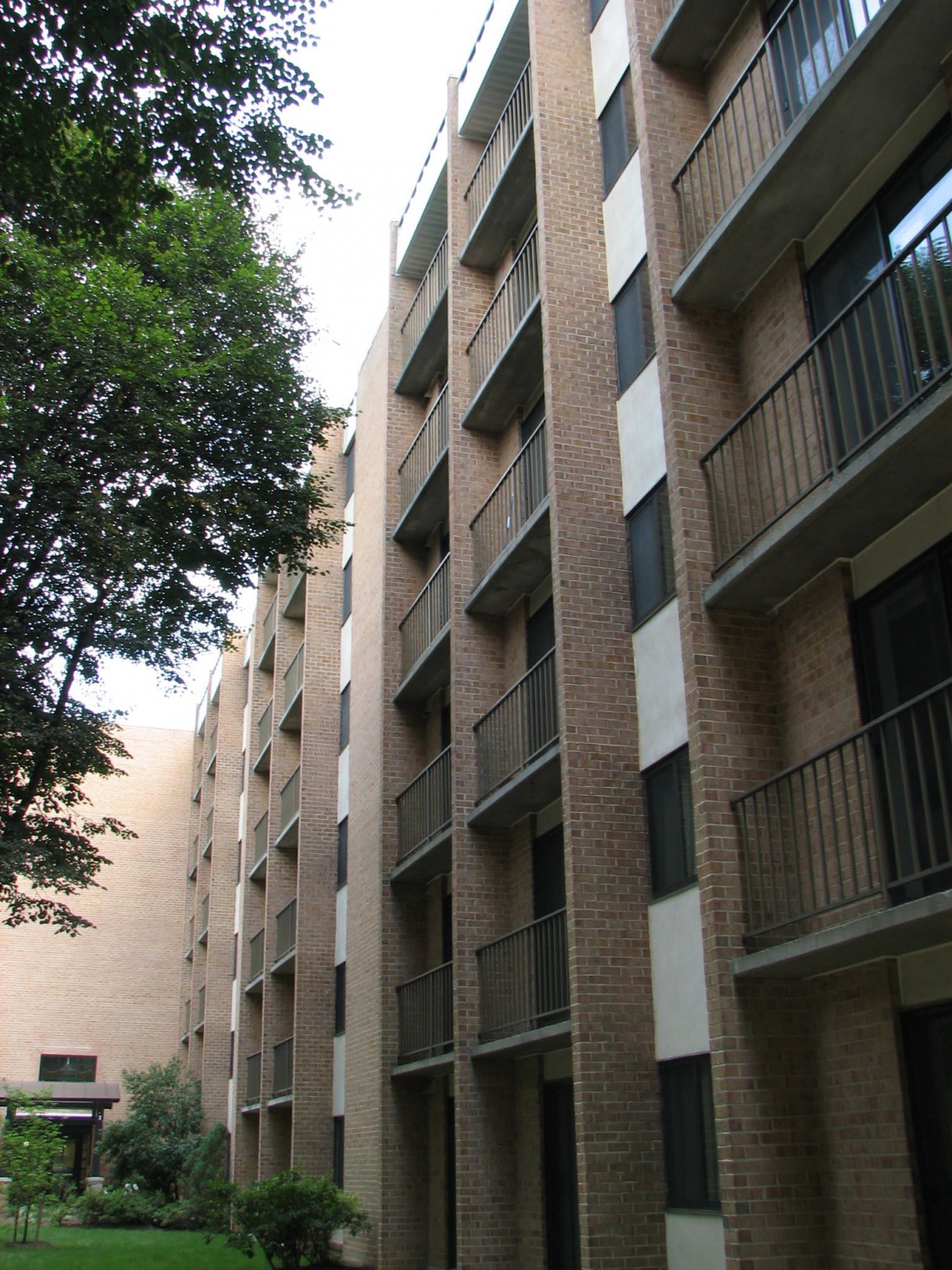 A multi-story residential apartment building with balconies and nearby trees.